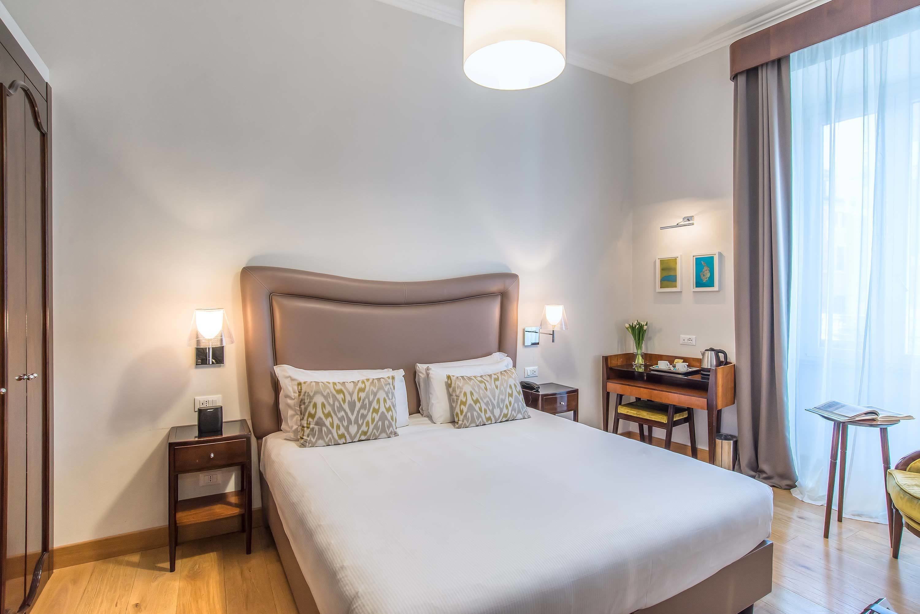 A hotel room with a large bed, bedside tables, a desk, and a chair.