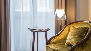 A room with a chair and a small table with a book. - Relais Rione Ponte (Rome)