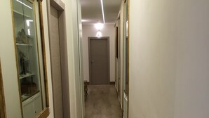 A narrow hallway with a wooden floor, white walls, and a door at the end. - Art Atelier Accomodation (Rome)