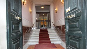 A grand staircase with marble steps and a red carpet leading to a glass door. - Art Atelier Accomodation (Rome)