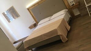 A bedroom with a wooden bed, a brick wall, and a small bedside table. - Art Atelier Accomodation (Rome)