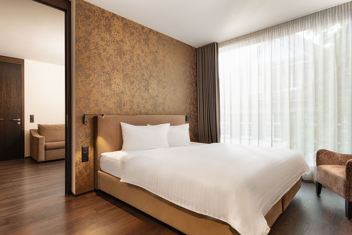 A hotel room with a large bed, a sofa, and a chair.