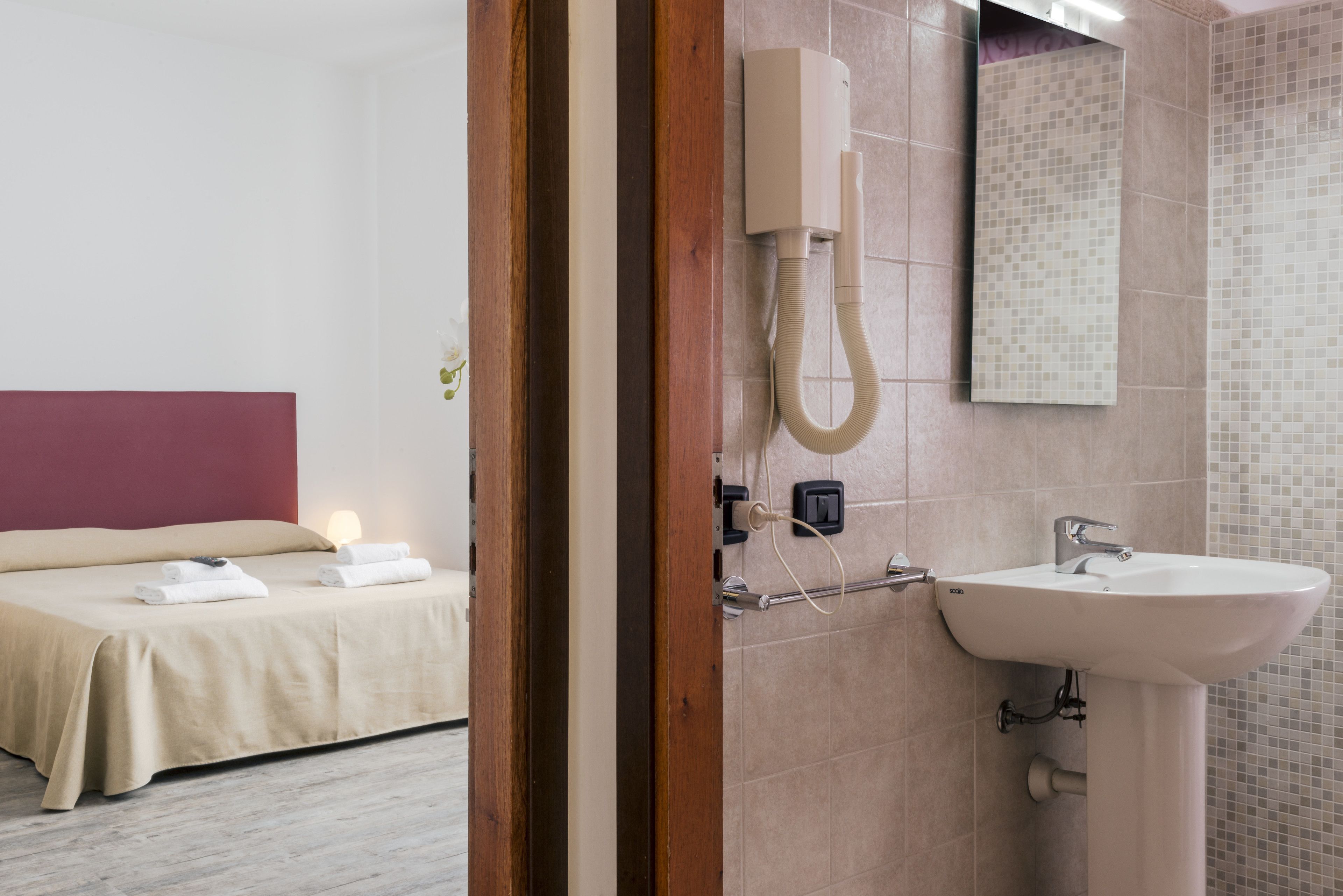Een hotelkamer met een bed, een badkamer met een wastafel en een douche.