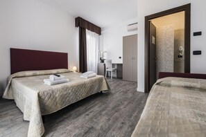 A hotel room with two beds, a desk, and a bathroom.