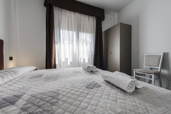 A hotel room with a large bed, a chair, and a wardrobe.