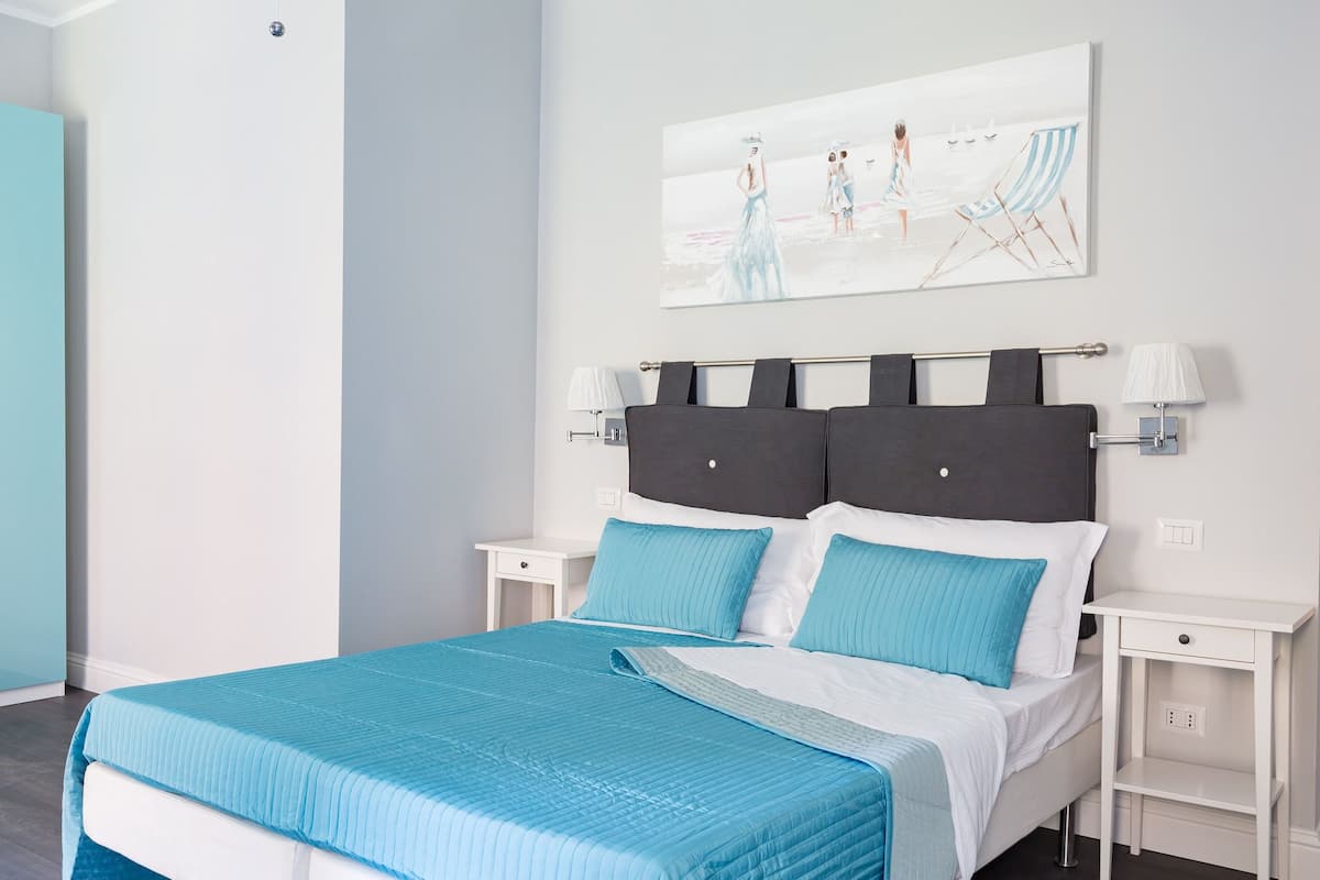 Ein modernes Schlafzimmer mit einem Bett, zwei Nachttischen, einer Kopfteil und einem Wandbild.