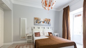 A hotel room with a large bed, a painting above the bed, a mirror, a nightstand, and a view of the outdoors through a window. - Residenza Vatican Suite (Rome)