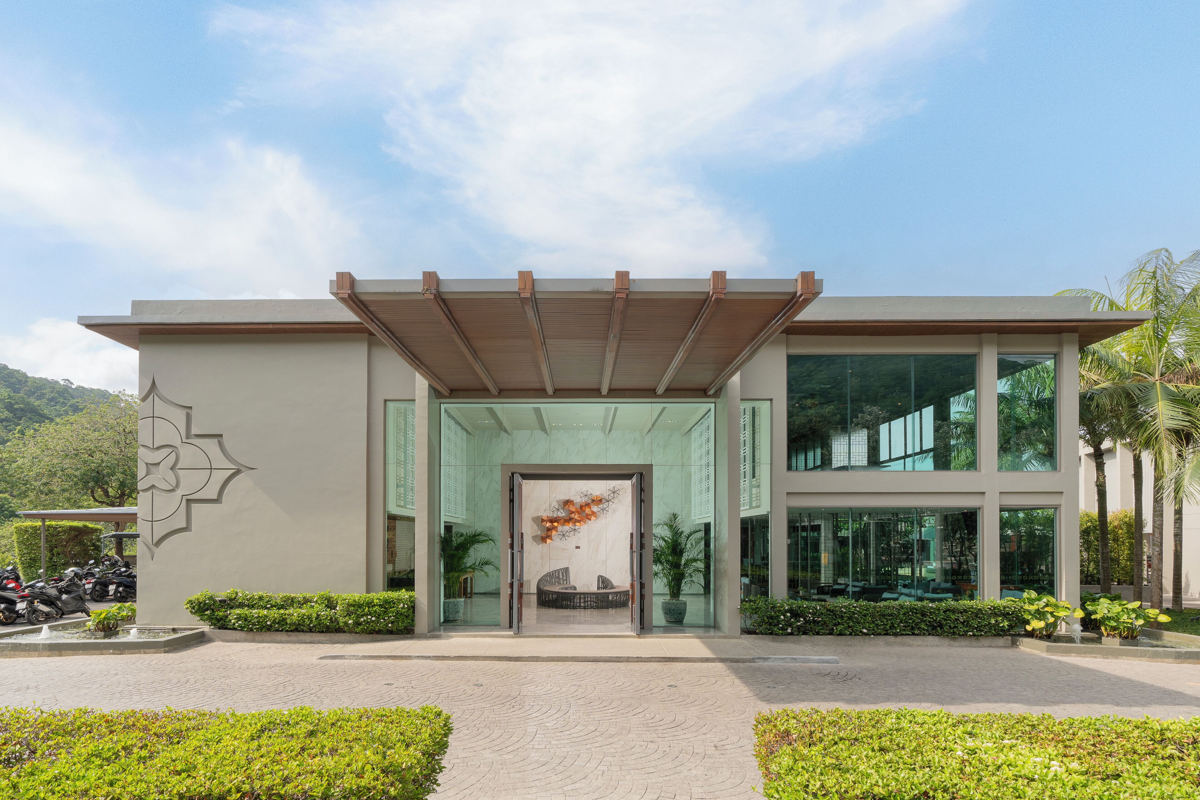 A modern building with a glass entrance, a covered porch, and a landscaped entrance area.