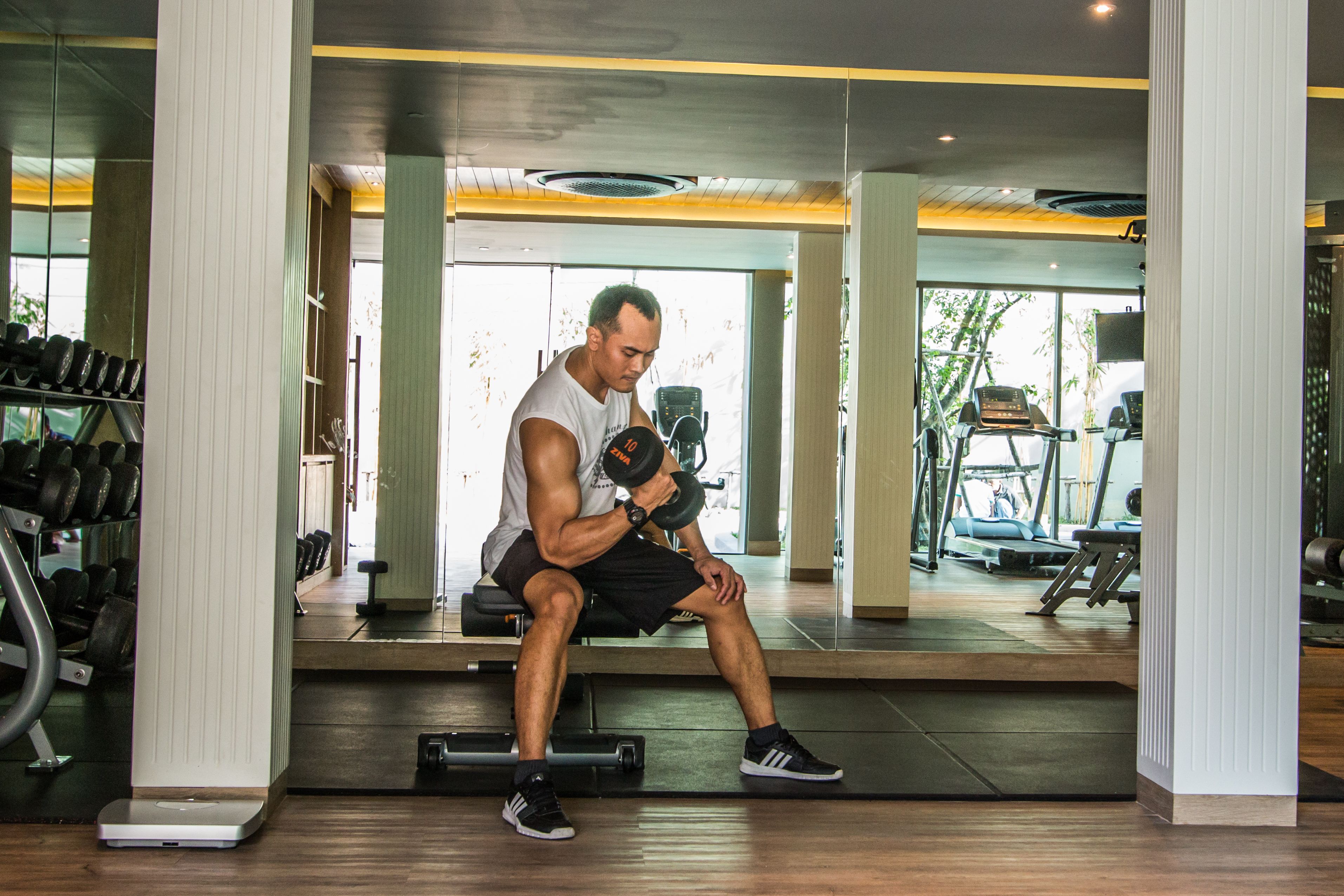 Un gimnasio con espejo, estantes para pesas y equipamiento de ejercicio.