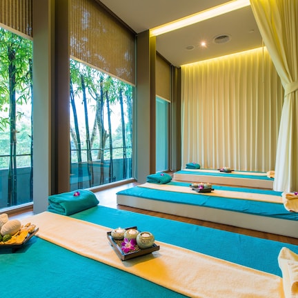 A spa room with multiple massage tables, each with a towel and a tray of amenities.