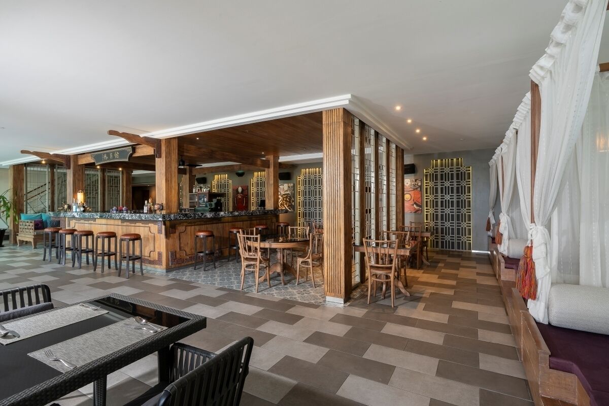 A spacious hotel lobby with a bar area, seating arrangements, and a staircase leading to other floors.