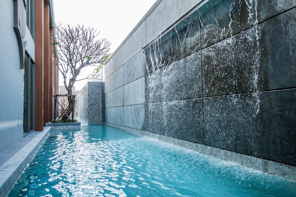 Una piscina al aire libre, sombrillas, sillones reclinables de piscina