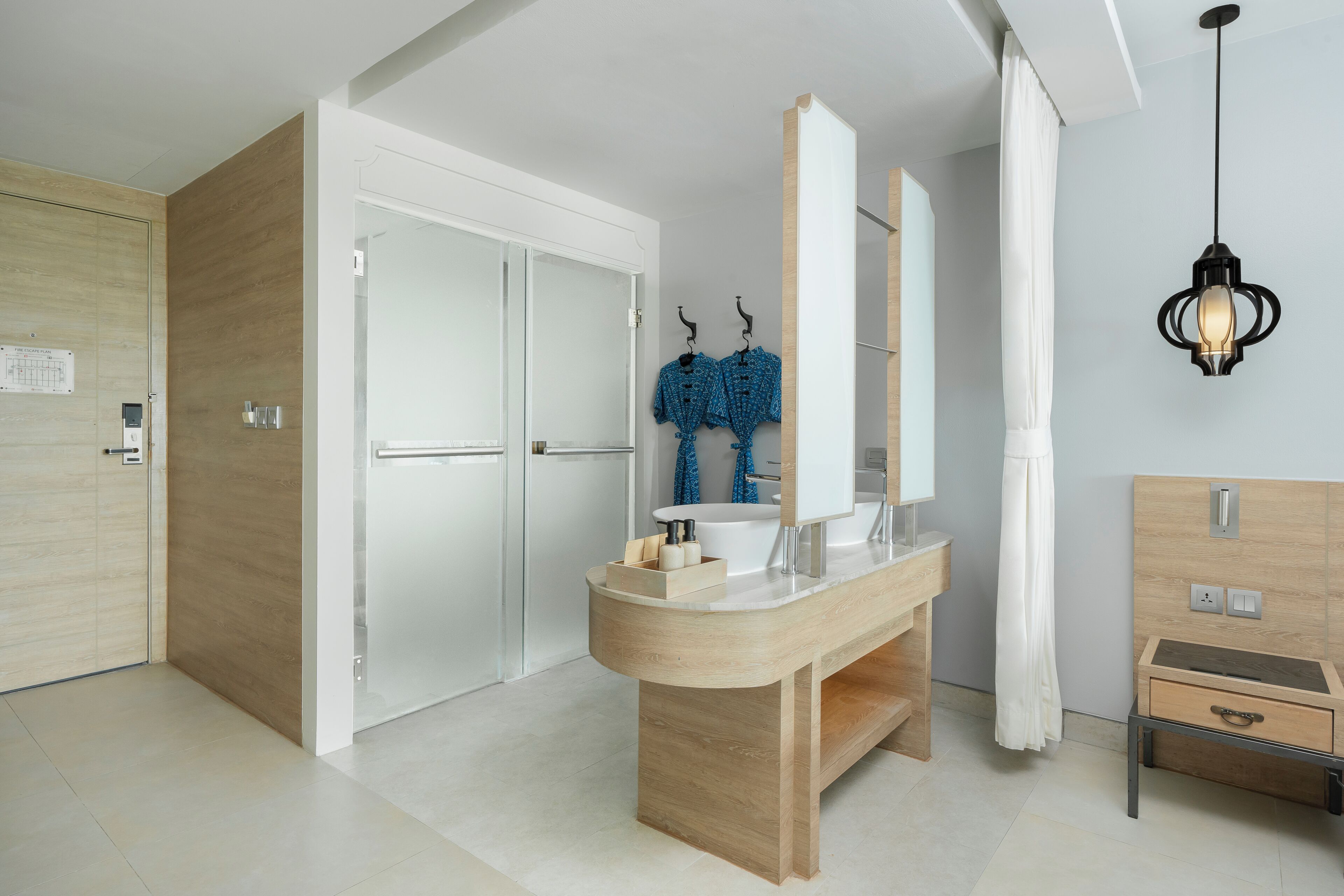 A modern bathroom with a wooden vanity, a large mirror, and a hanging light fixture.