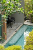 A swimming pool with a tiled edge, two chairs, and a small table.