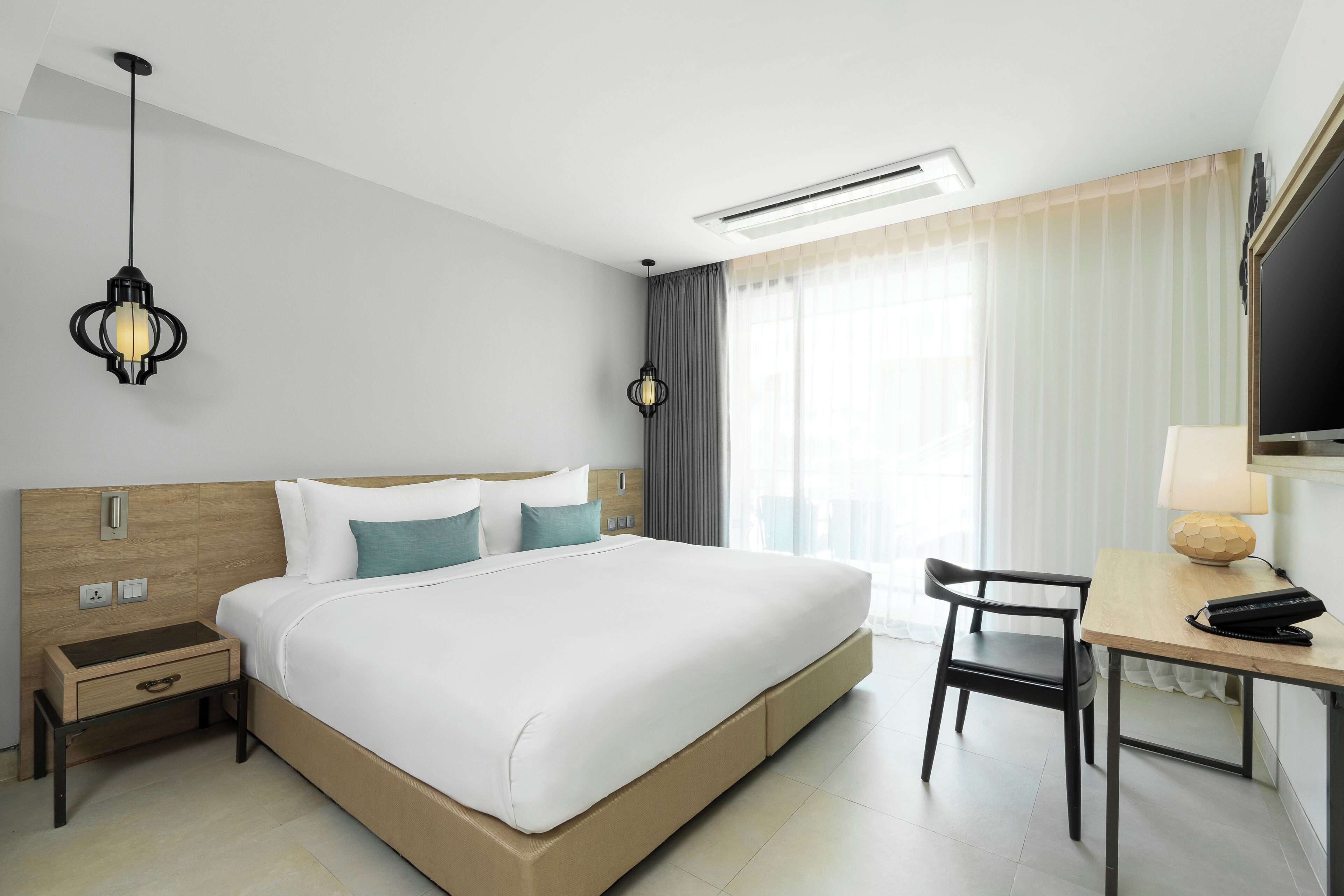 Une chambre d’hôtel comprenant un lit, une table de chevet, une lampe, une chaise et un téléviseur.