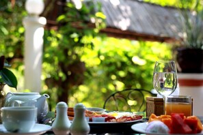 A table set with a teapot, cups, a glass of water, a plate of food, and a glass of orange juice. - Tropical Hill Kep (Kep)