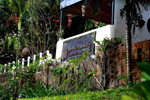 A sign for Tropical Hill-Kep Campu, surrounded by lush greenery and a white fence. - Tropical Hill Kep (Kep)