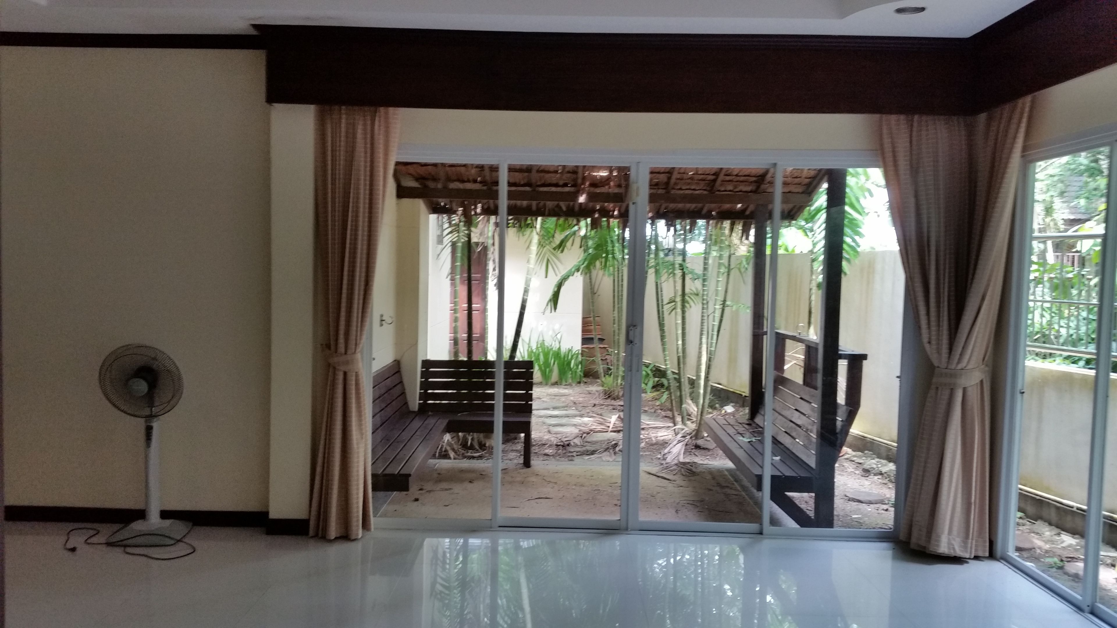 Una habitación con puerta corrediza de vidrio que da a un espacio exterior con banco y plantas.