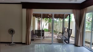 A room with a sliding glass door leading to an outdoor area with a bench and plants.