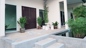 A modern building with a large entrance, potted plants, and a small pool area.