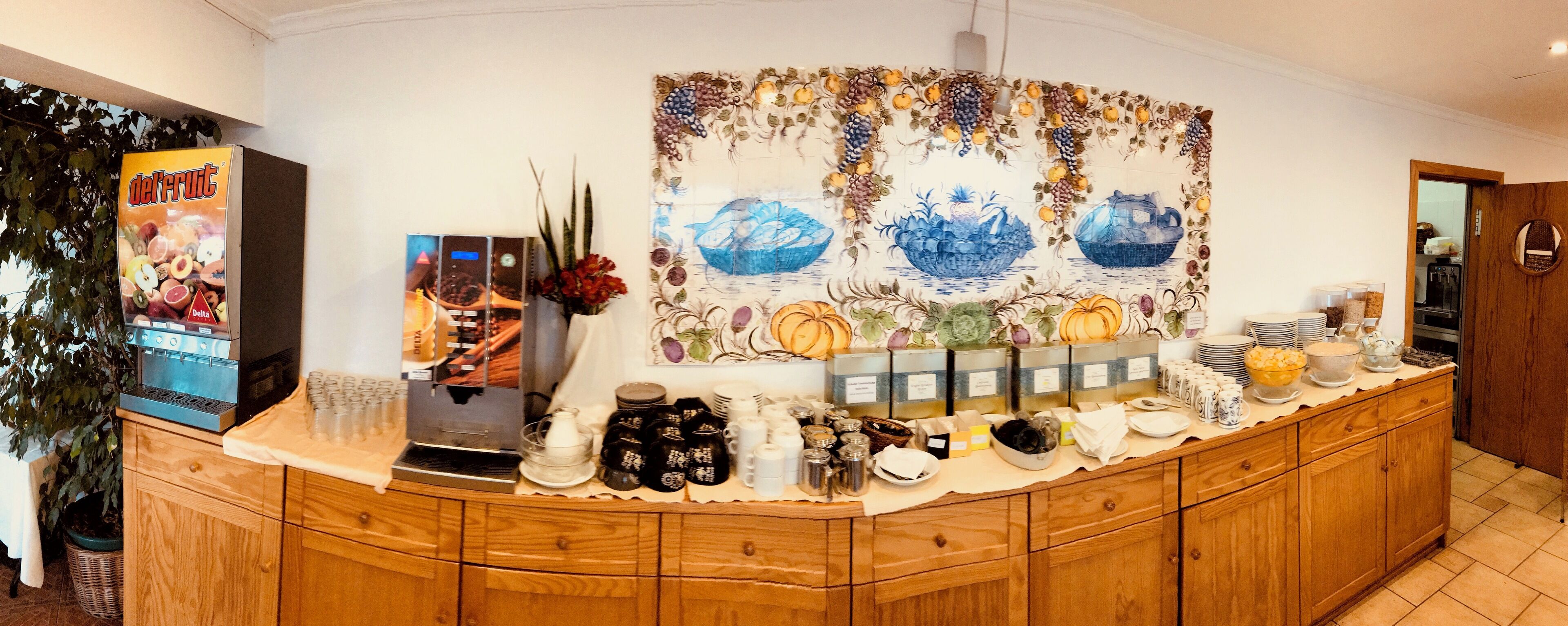 A breakfast bar with a coffee machine, a fruit display, and a decorative wall piece.