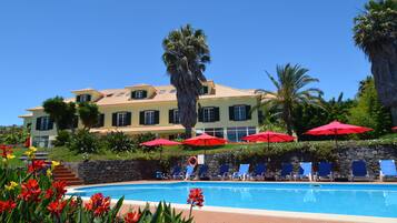 Una piscina al aire libre, sombrillas, sillones reclinables de piscina