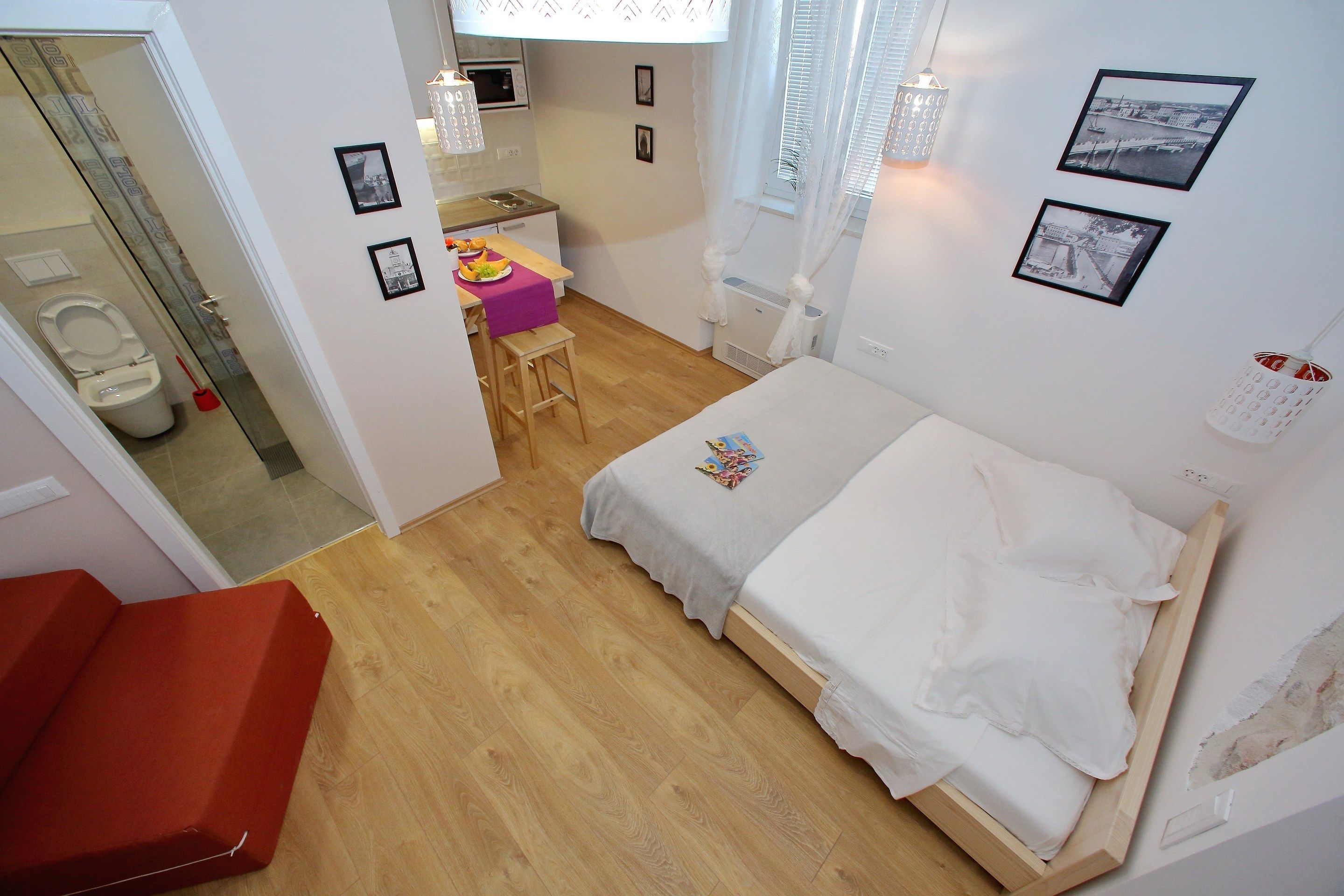 A compact room with a bed, a small kitchenette, a bathroom, and a staircase.