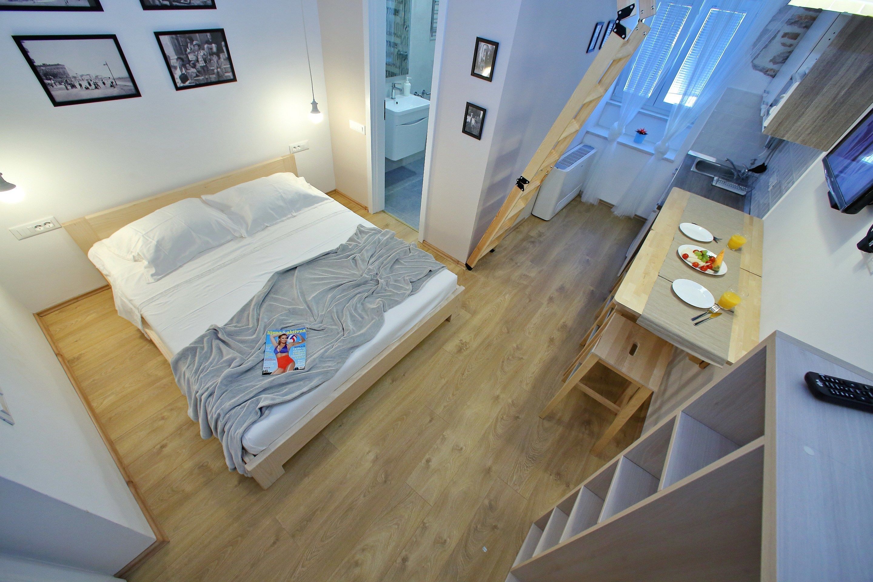 Un dormitorio con una cama, una mesita de noche con lámpara y un escritorio pequeño con silla.