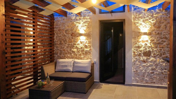 A cozy outdoor seating area with a wicker sofa and a wooden slatted partition. - Guverna New City Accommodation (Zadar)