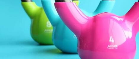 Tres kettlebells de diferentes colores, con la marca "APUS Sports" visible.