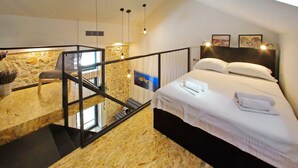 A bedroom with a bed, a small seating area, and a balcony with a view. - Guverna New City Accommodation (Zadar)