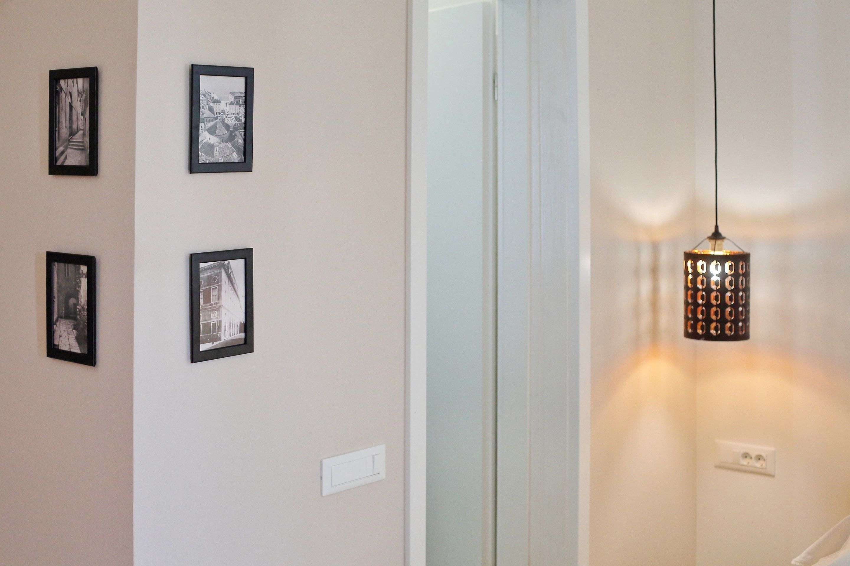 Un pasillo con cuatro fotografías enmarcadas en la pared y una lámpara colgante.