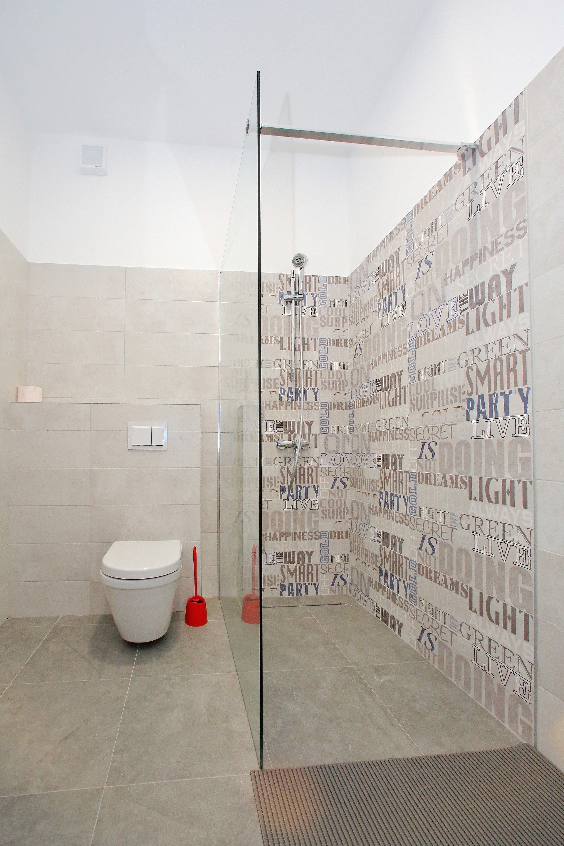 A modern bathroom with a glass shower enclosure, a toilet, and a tiled floor.