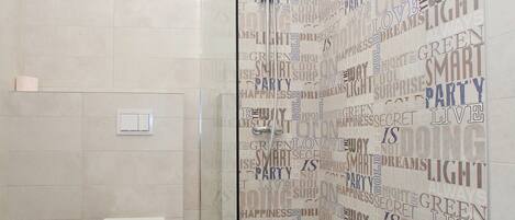 A modern bathroom with a glass shower enclosure, a toilet, and a tiled floor.