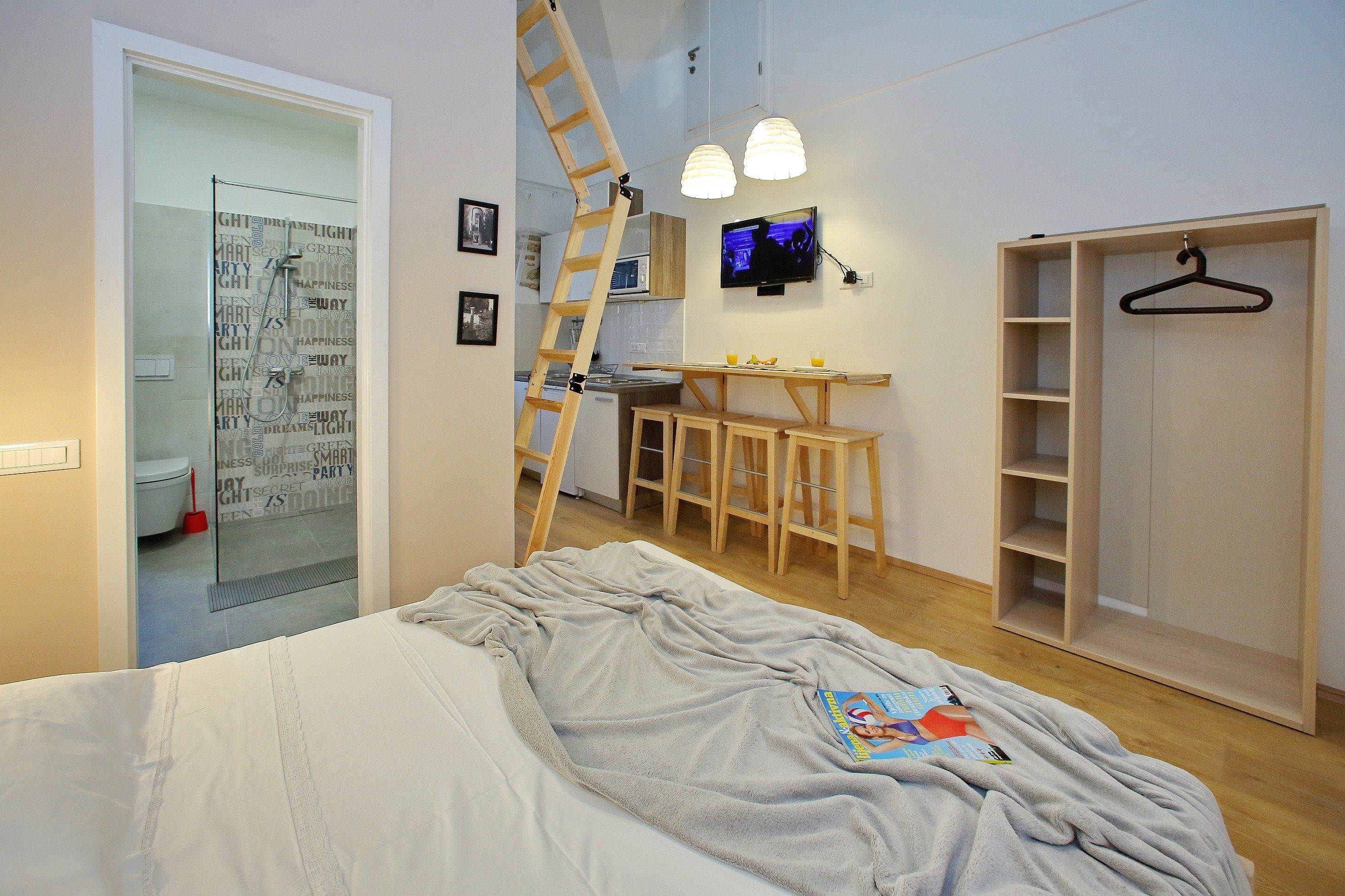 A bedroom with a bed, a desk, a TV, and a wardrobe.