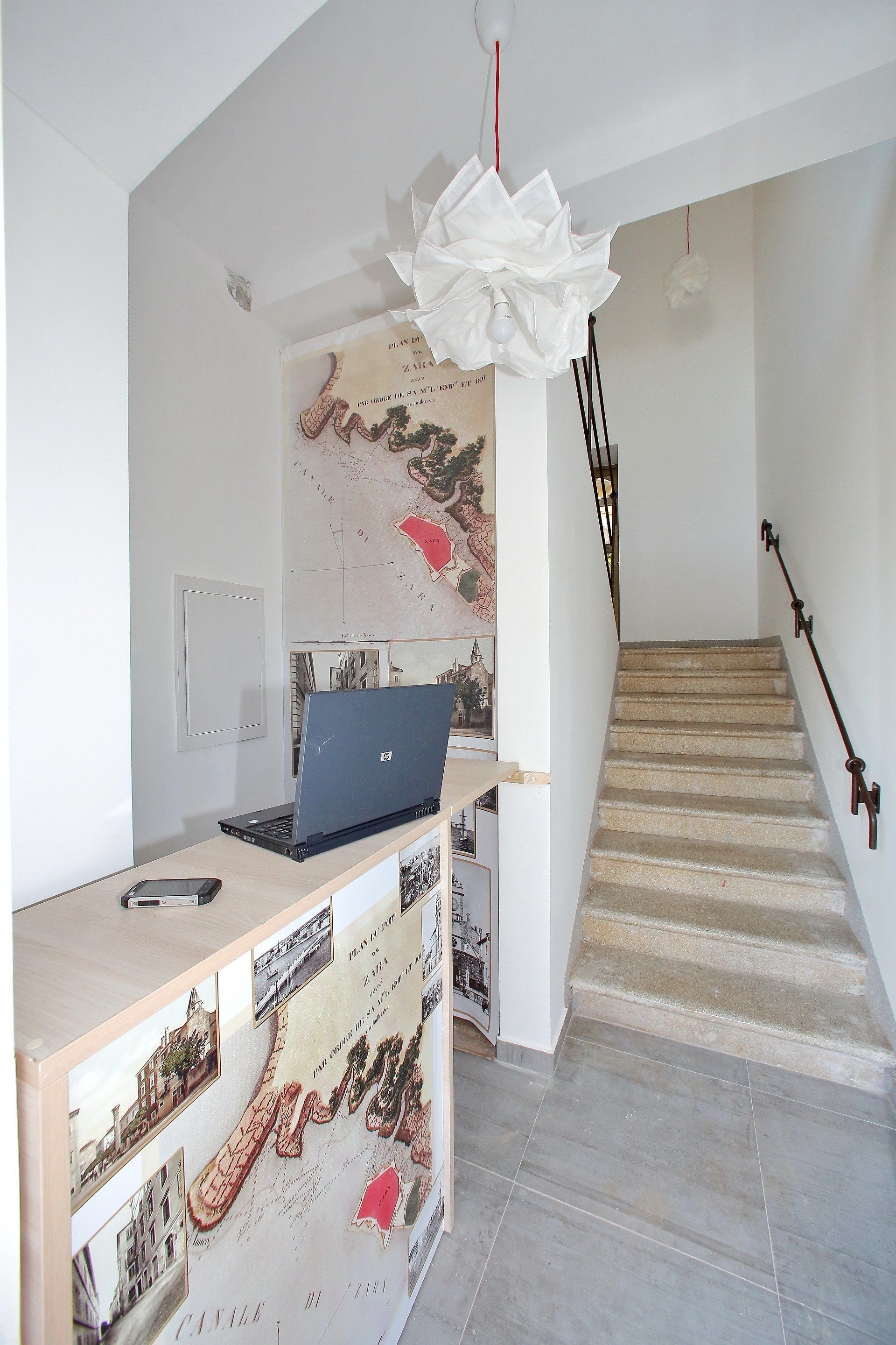 Un interior moderno con una computadora portátil sobre un escritorio, un mapa en la pared y una escalera.