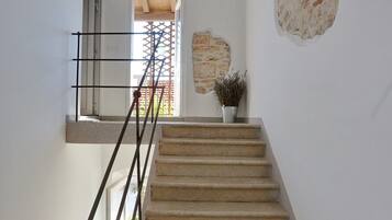 Una escalera con barandilla, una planta en maceta y una pared con un diseño de piedra texturizada.