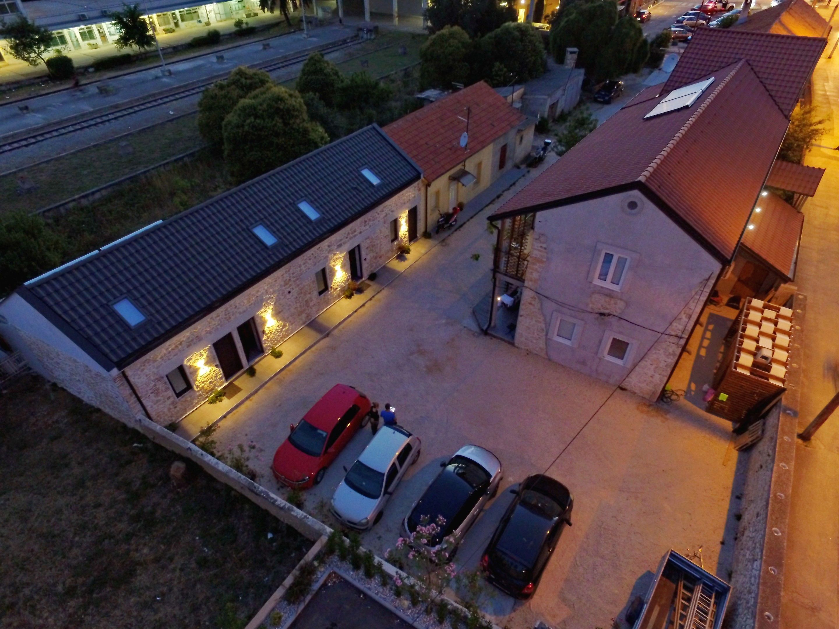 Ein Luftbild zeigt eine Wohngegend mit einem zweigeschossigen Haus, einem Parkplatz mit vier Autos und einem Bahnstrecke im Hintergrund.