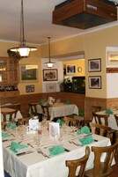 Un restaurante con varias mesas dispuestas para comer, sillas de madera y lámparas colgantes.