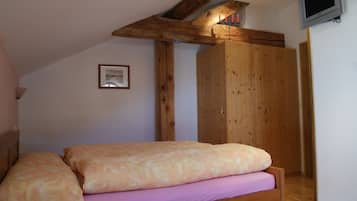 A bedroom with a wooden bed, a wardrobe, and a television mounted on the wall.