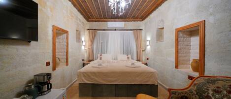 A bedroom with a bed, a TV, a coffee maker, a sofa, and a chandelier.