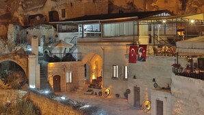 A historic building with a courtyard, stone walls, and a balcony with chairs.