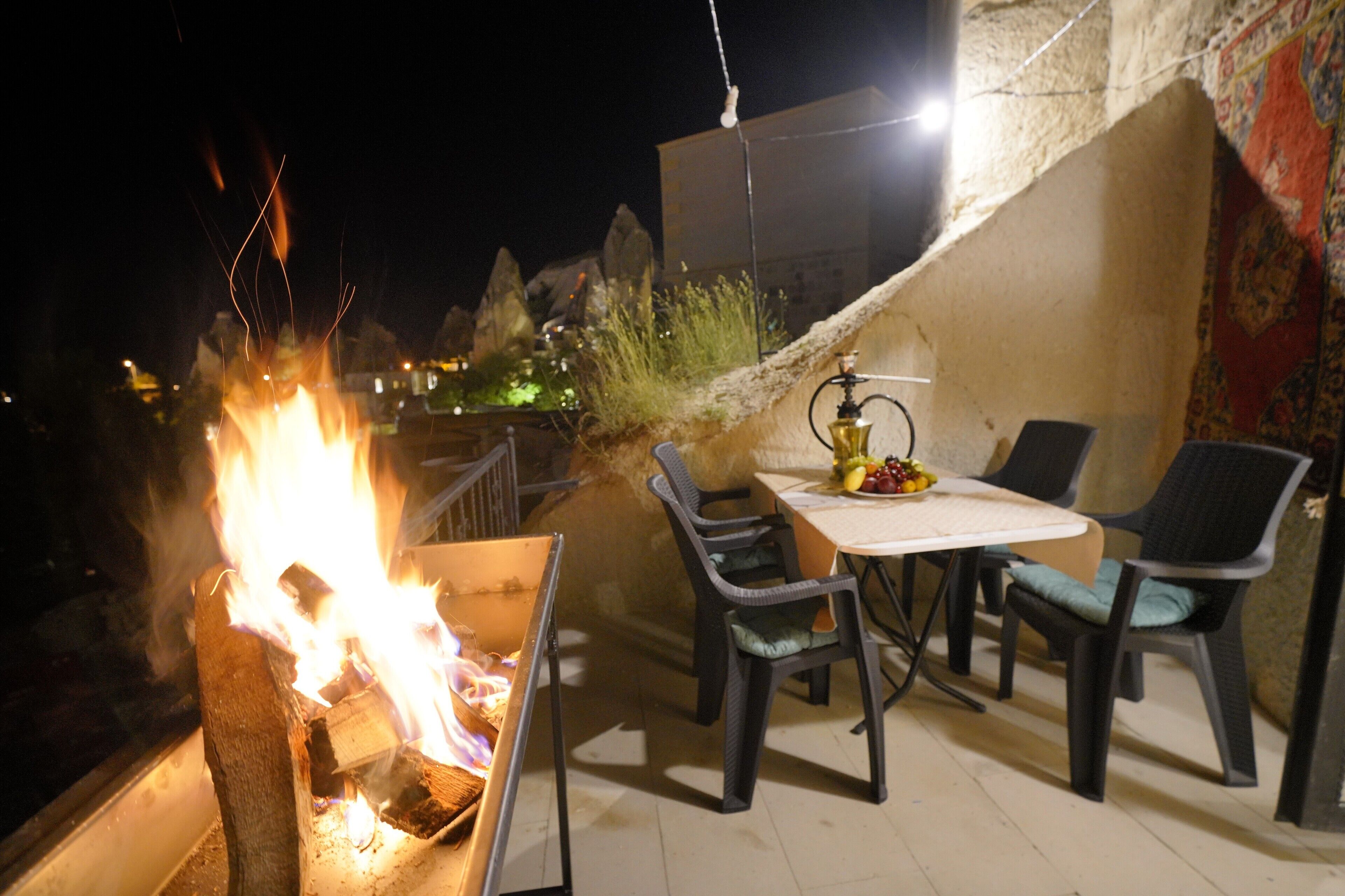An outdoor dining area with a fire pit, chairs, and a table set for two.