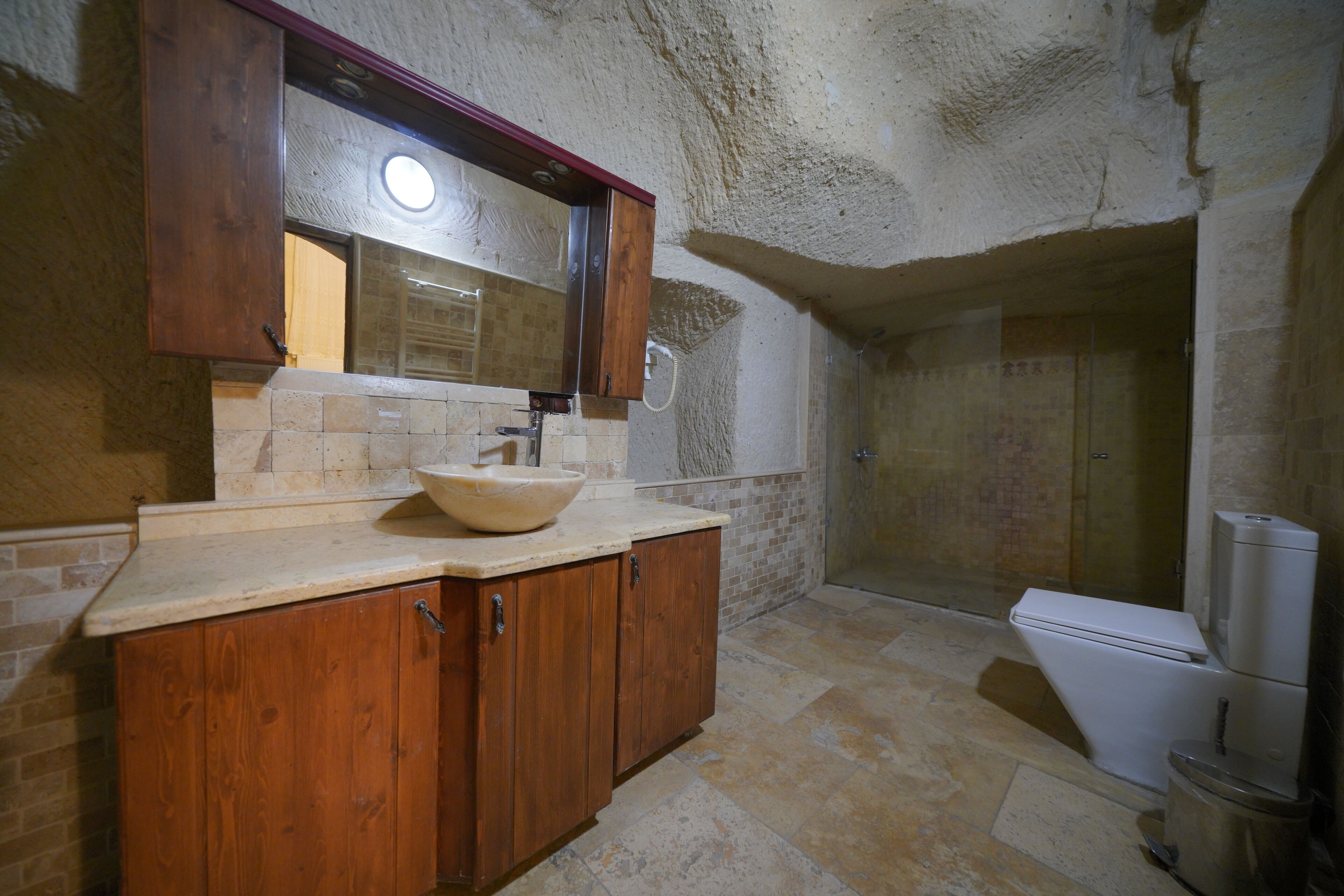 A bathroom with a wooden vanity, a sink, a mirror, and a toilet.