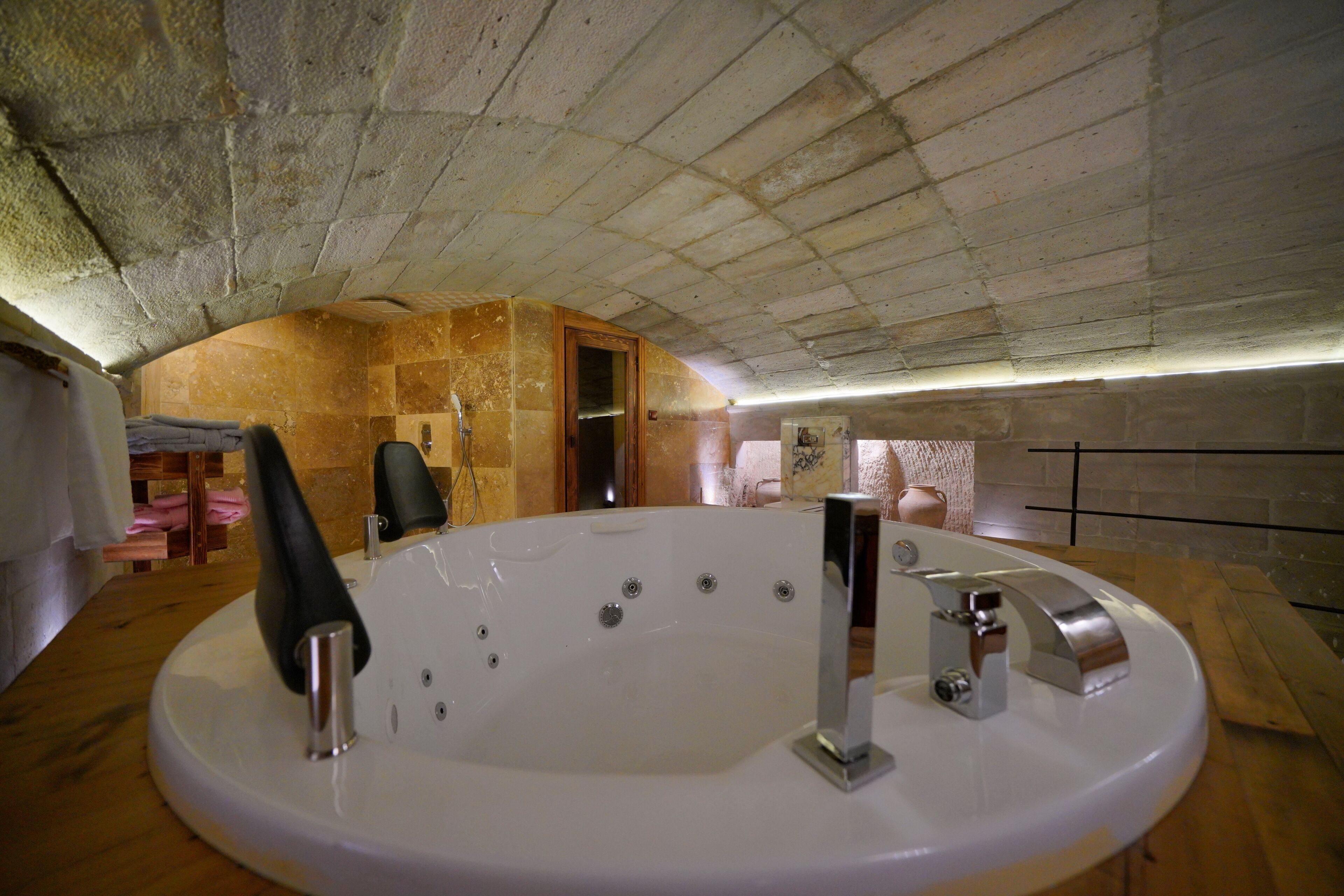 A modern bathroom with a freestanding bathtub, a wooden vanity, and a stone wall.