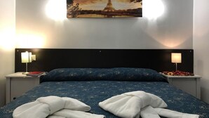 A hotel room with a bed, two bedside tables, a painting of the Eiffel Tower, and two lamps. - Locanda Otello (Rome)