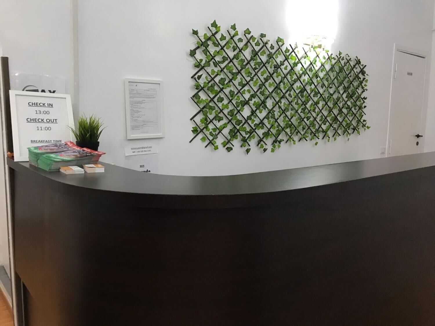 A reception desk with a check-in/check-out sign, a menu, and a Wi-Fi sign. - Locanda Otello (Rome)