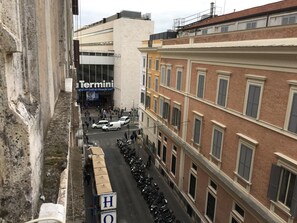 Vista de la calle con un edificio identificado como 'Termini' al fondo, una fila de motocicletas estacionadas y un cielo despejado.