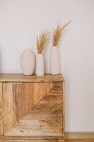 Eine Holzschrank mit zwei weißen Vasen, gefüllt mit getrockneten Pflanzen.