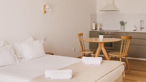 A minimalist bedroom with a bed, bedside table, and a dining area with chairs. - Pure Flor de Esteva (Vila do Bispo)